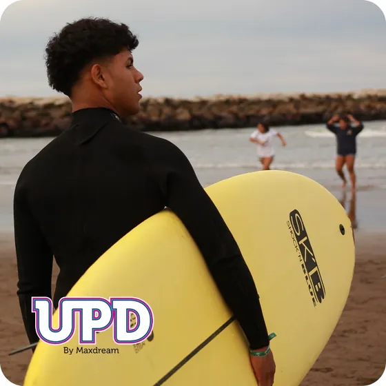 Egresado con tabla de surf en la playa
